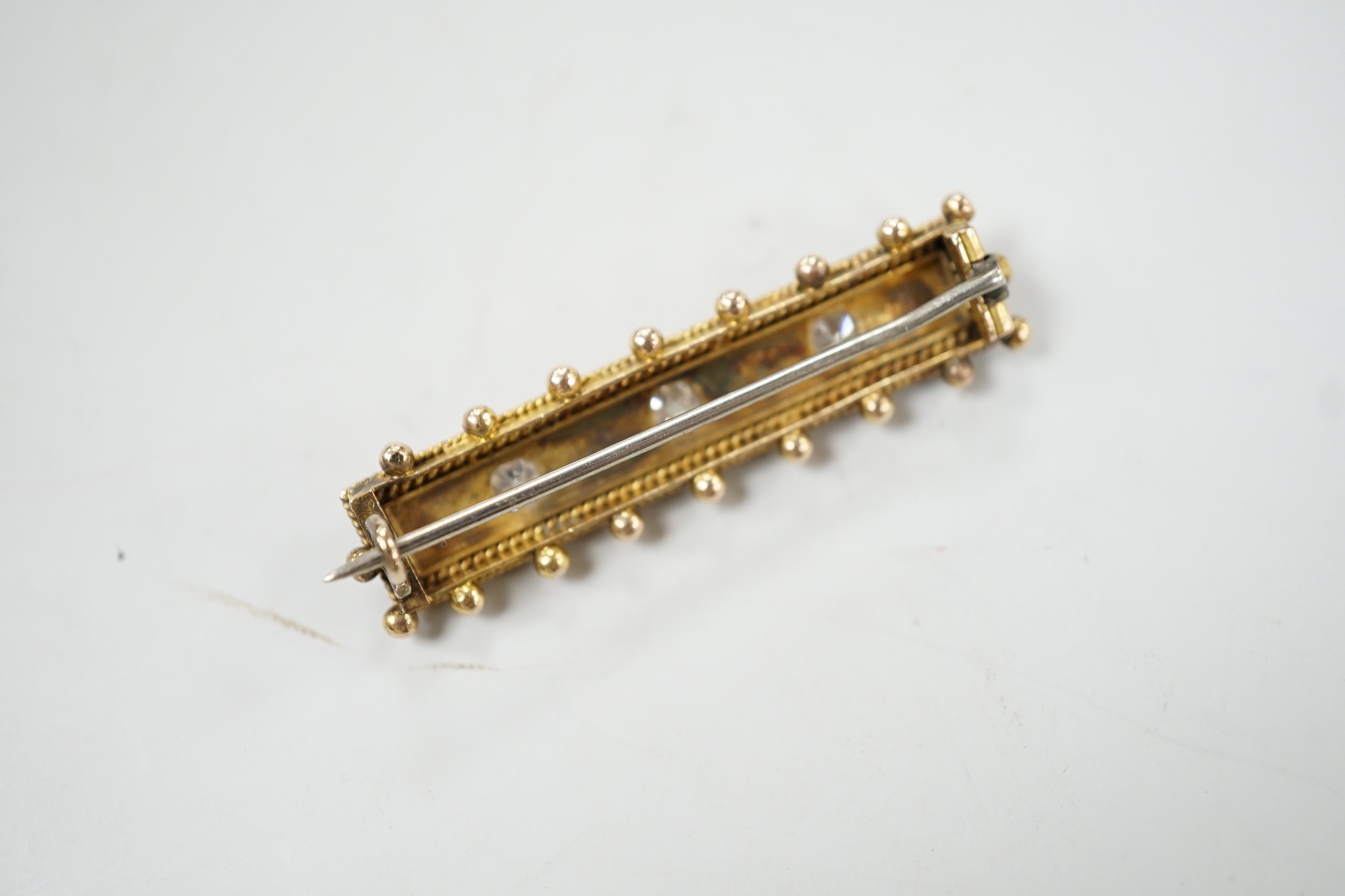 An early 20th century yellow metal, three stone diamond and four stone split pearl set bar brooch, 44mm, gross weight 6.8 grams.